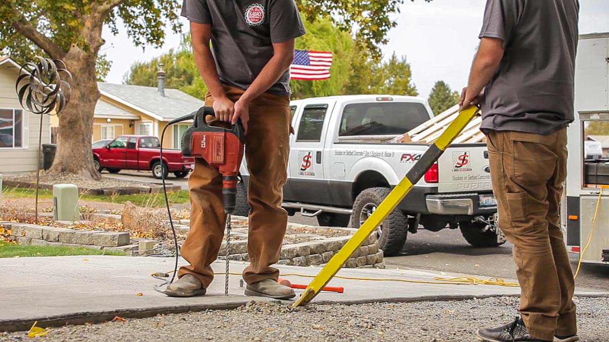 2 men using tools to repair concrete floor slabs